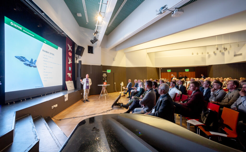 Henkilö yleisön edessä pitämässä esitystä auditoriossa